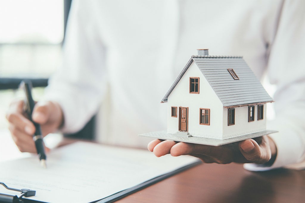  A person is holding a model house in the palm of their hand.