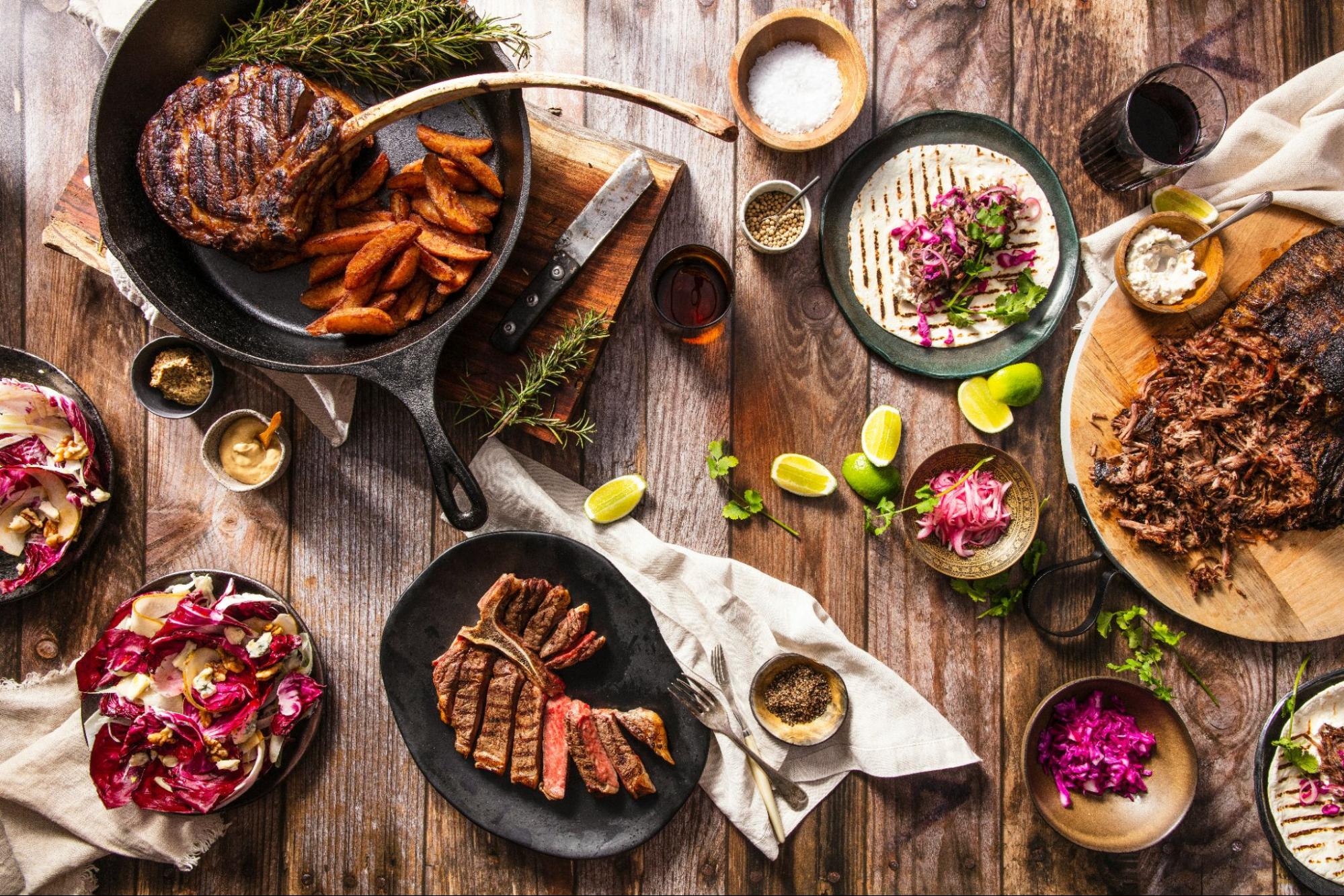 A stunning, top-down view of a rustic dinner party food spread, a great hosting hack for a 'gourmet BBQ' or 'taco night' theme.