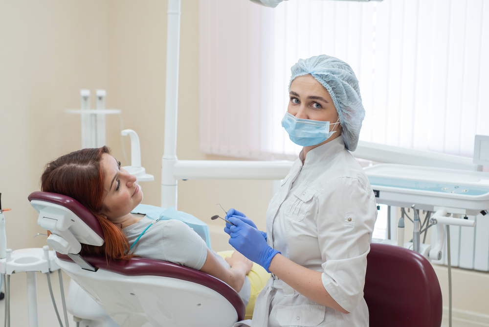 Dentist beside a patient reclining in a dental chair before treatment.