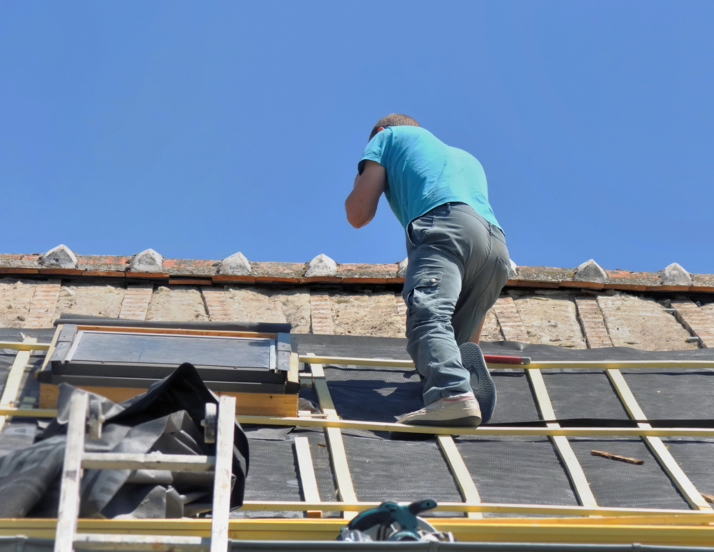 Nsw slate roofing professional inspecting and repairing a slate roof surface around a skylight for new tile install.