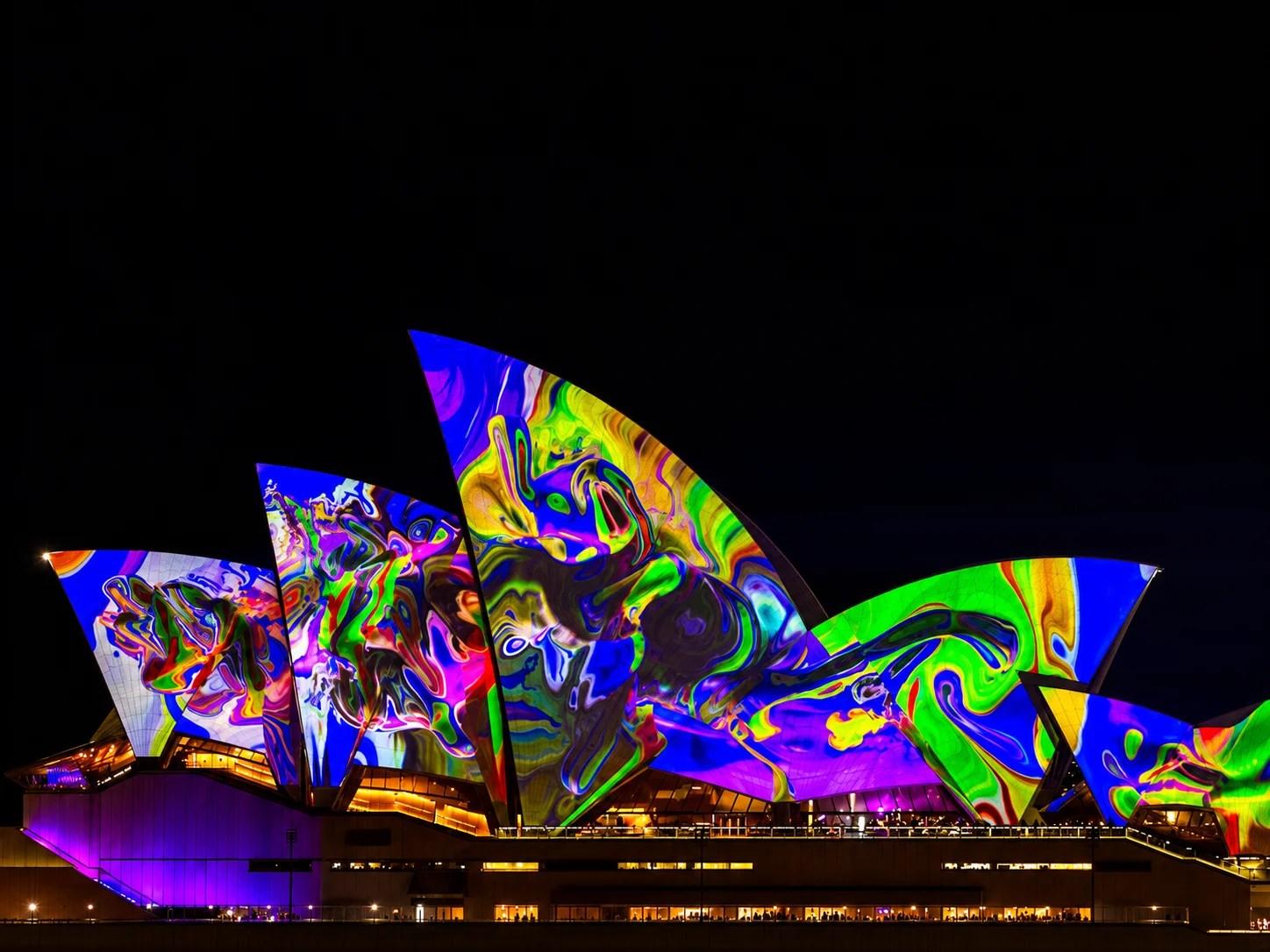 Sydney Opera House illuminated with colourful lights at night, one of Sydney's top attractions.