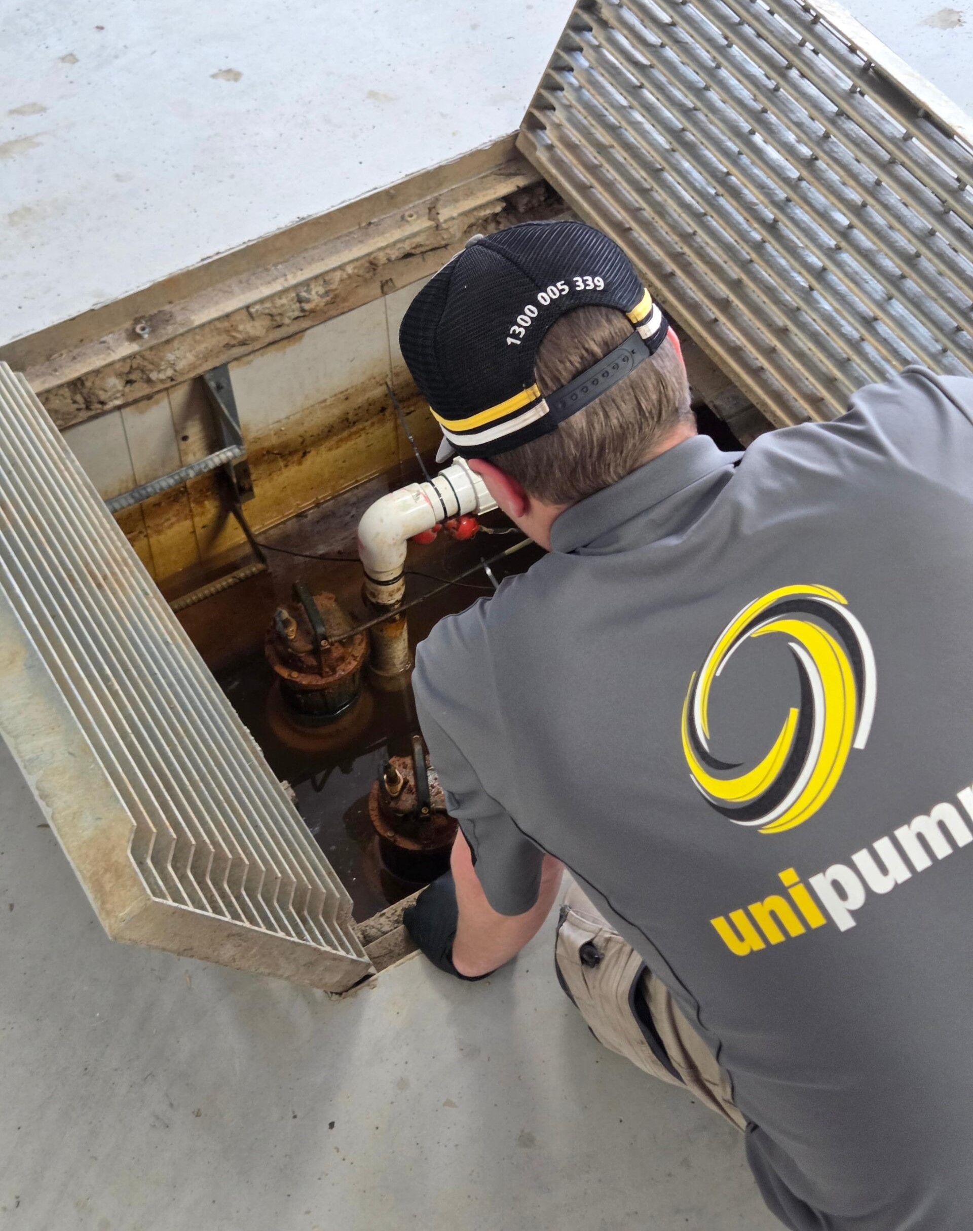 UniPump technician inspecting pumps and pipework with visible corrosion inside an open pump pit.